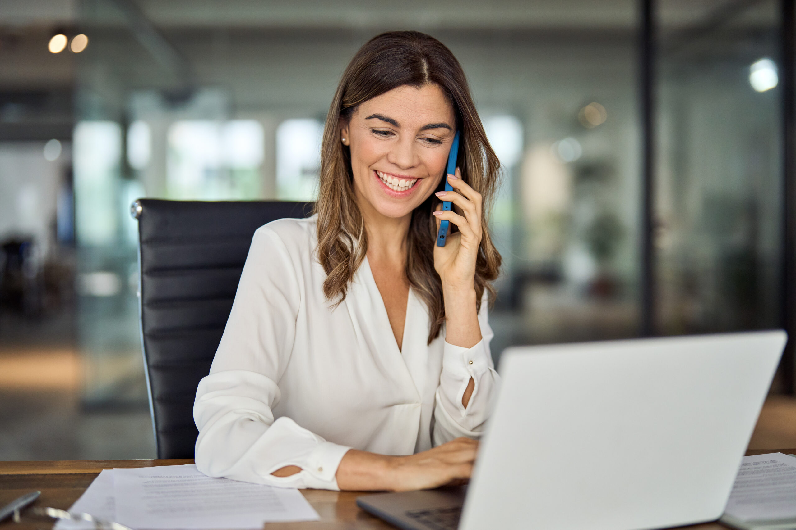Woman smiling on the phone in front of computer