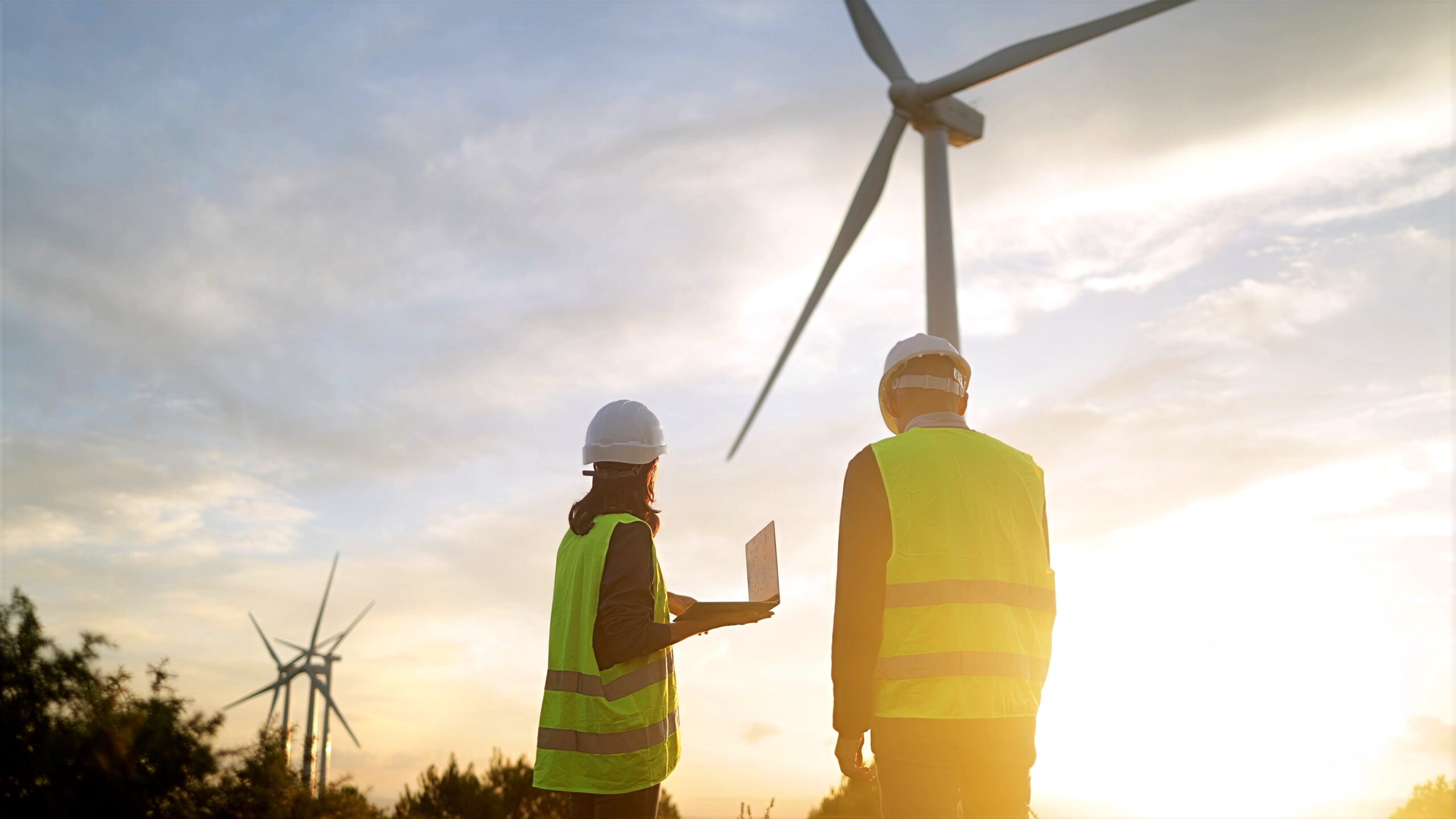 Two people looking up at wind turbine