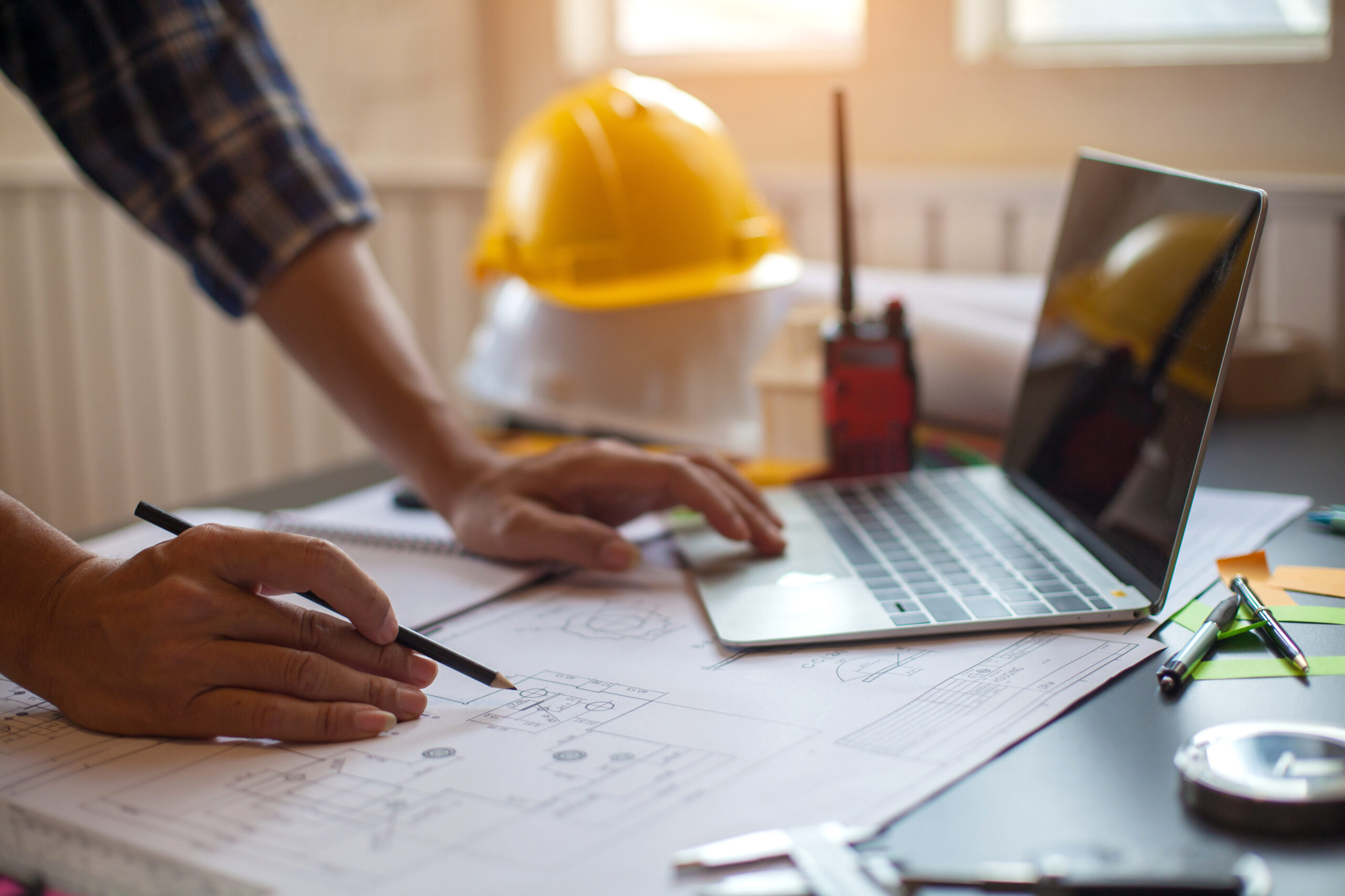 Person working on computer with hard hat in the background